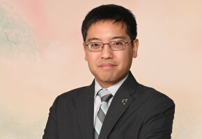 Photo of SEAS alum Eugene Beh, A.B./A.M. ‘09, wearing a grey suit and striped tie