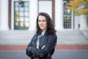 Image of Harvard SEAS alum Raquel Schreiber, S.B. '15, MS/MBA '21, wearing a black jackket and blue shirt in front an outdoor staircase