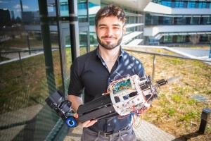 Harvard SEAS senior Ben Schroeder holding a robotic hand attachment built for a senior capstone project