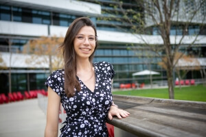 Harvard SEAS graduate student Maria Emilia Mazzolenis wearing a black and white dress standing in front of the Science and Engineering Complex next to a tree