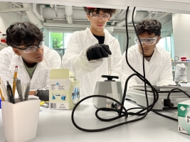 High school students Dominic Jorge, Oishik Chakraborty, and Kabir Gokarn working at a lab table