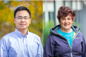 Two individuals outside; the person on the left is wearing a light blue shirt, and the person on the right is wearing a jacket and a blue shirt.