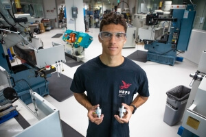 Harvard SEAS student Nathan Evans holding two metallic rocket valves