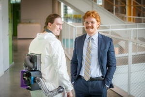 Harvard SEAS students John Pojman and Jack Shea wearing a blue business suit and white lab suit with an air conditioner on the back