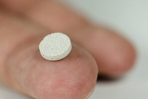 porous biomaterial scaffold the size of an aspirin tablet on tip of finger