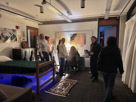 A group of Harvard students in an art installation designed like a bedroom